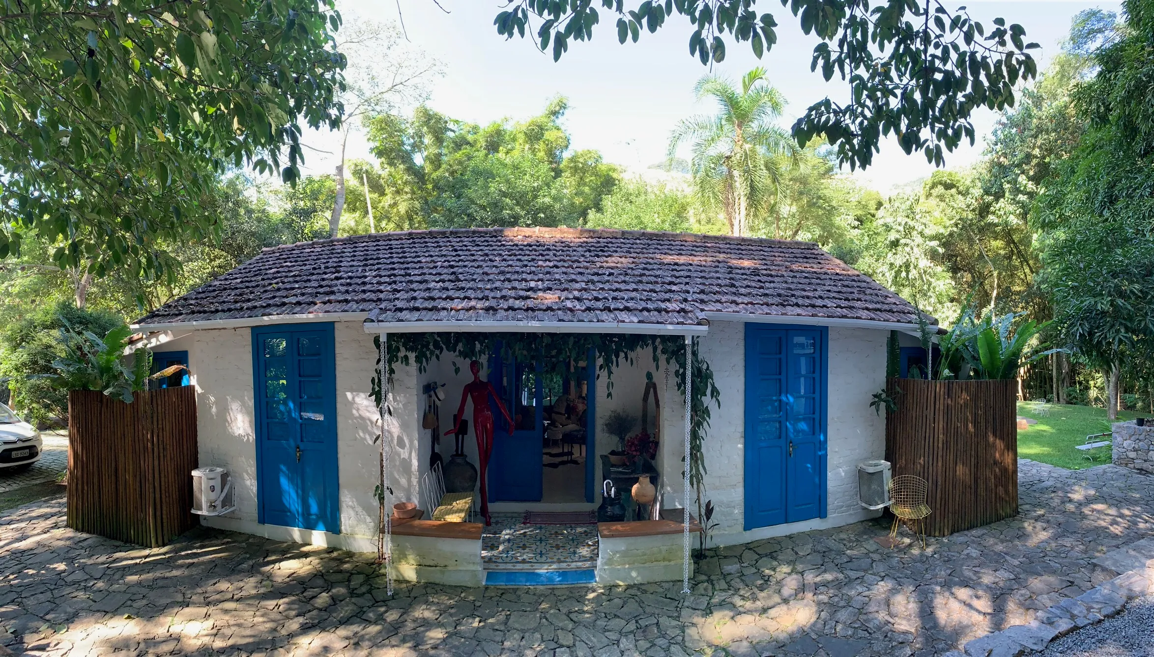 A Casa do Colono de frente: paredes caiadas, portas azuis e o pátio de pedra sob o telhado de telha antiga.
